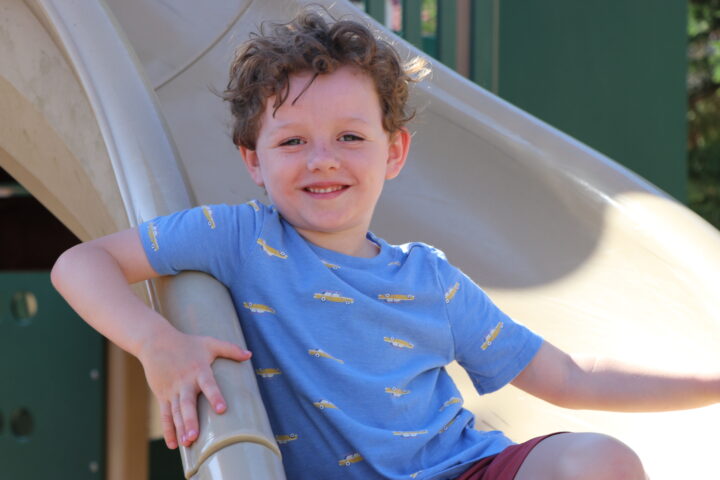 A young boy on a slide at a playground.