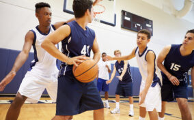 A group of young men playing basketball in a gym.
