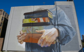 A mural of a hand holding books on a building.