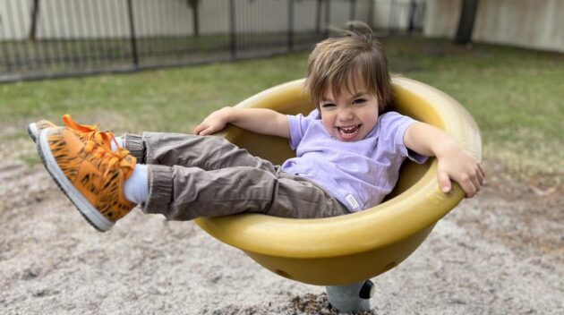 A little boy sitting in a yellow seat.