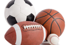 A soccer ball, basketball, football, and baseball are grouped together on a white background.