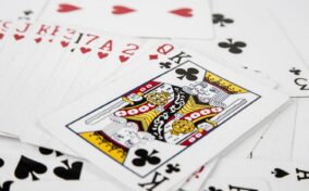 A close-up of playing cards scattered on a surface, with the King of Clubs prominently displayed on top.