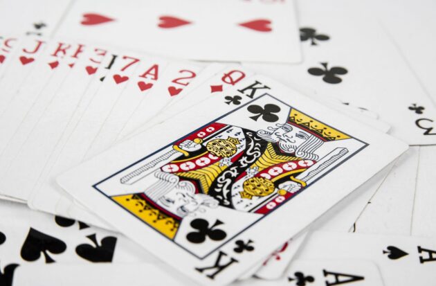 A close-up of playing cards scattered on a surface, with the King of Clubs prominently displayed on top.