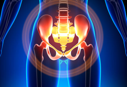 Digital illustration showing the lower torso and pelvis with a focus on the hip joints and pelvic bones, highlighted in red and orange to indicate pain or inflammation.