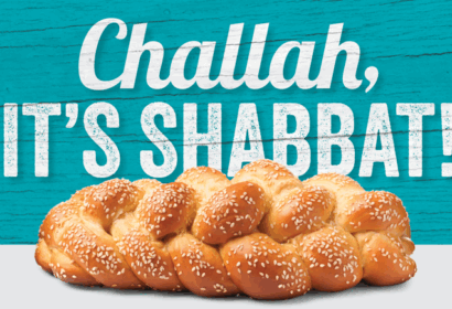 A braided loaf of challah bread sits in front of a turquoise background with the text "Challah, It's Shabbat!" in bold white letters.