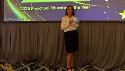 A woman stands holding a plaque in front of a large screen displaying "Kerstin Teutonico, 2025 Preschool Educator of the Year," with her photo and a gold star graphic.