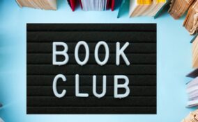 A black letterboard with "BOOK CLUB" in white letters is surrounded by open books arranged in a circle on a blue background.
