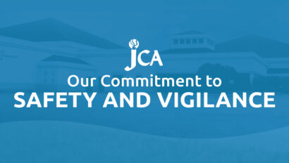 Blue graphic with the text "JCA Our Commitment to SAFETY AND VIGILANCE" displayed over a subtle background of a building.